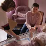 Soin palliatif domicile : infirmière ajuste un lit médical, proche tient la main du patient